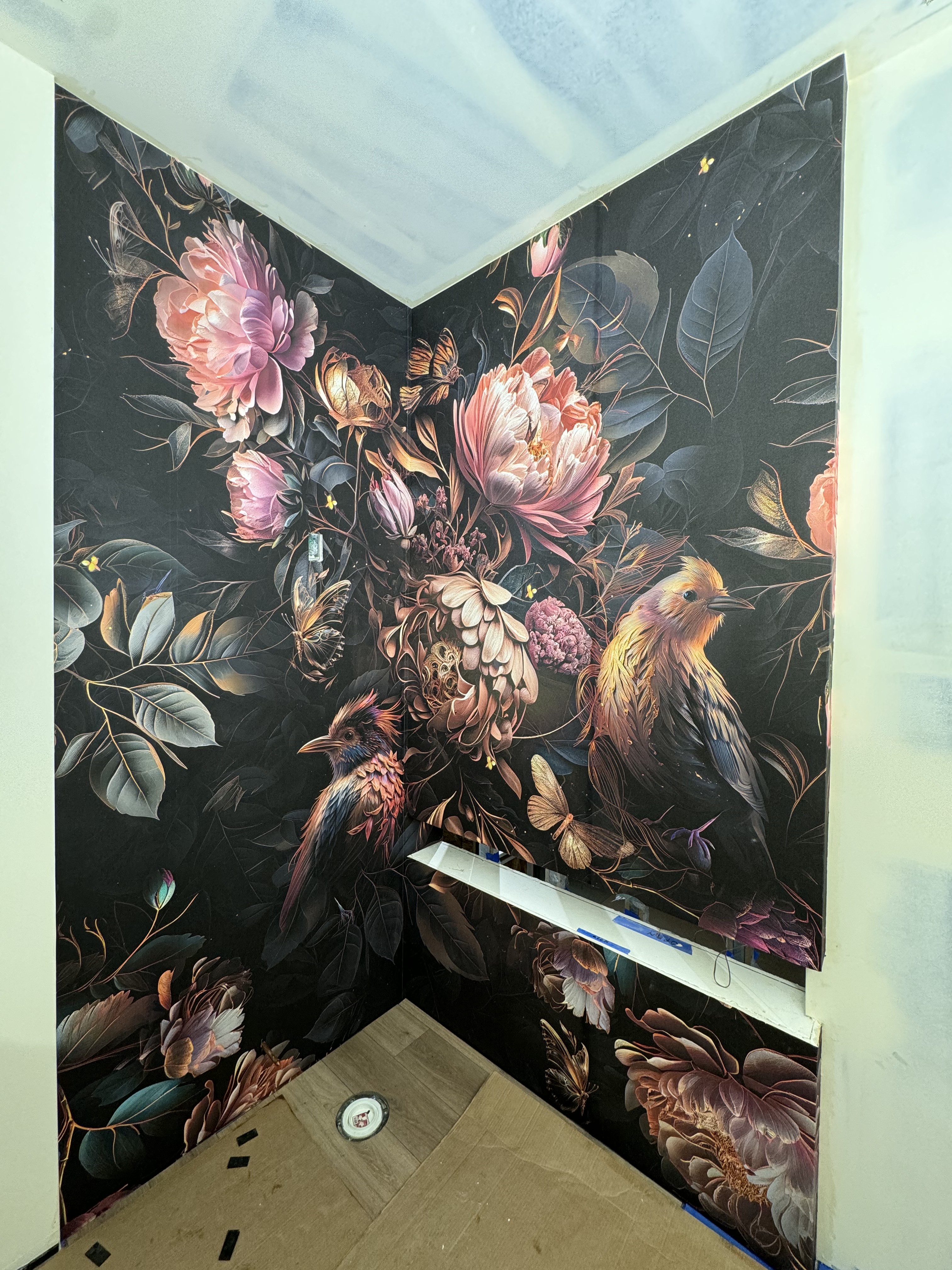 Dark floral mural with birds and butterflies installed across a powder room