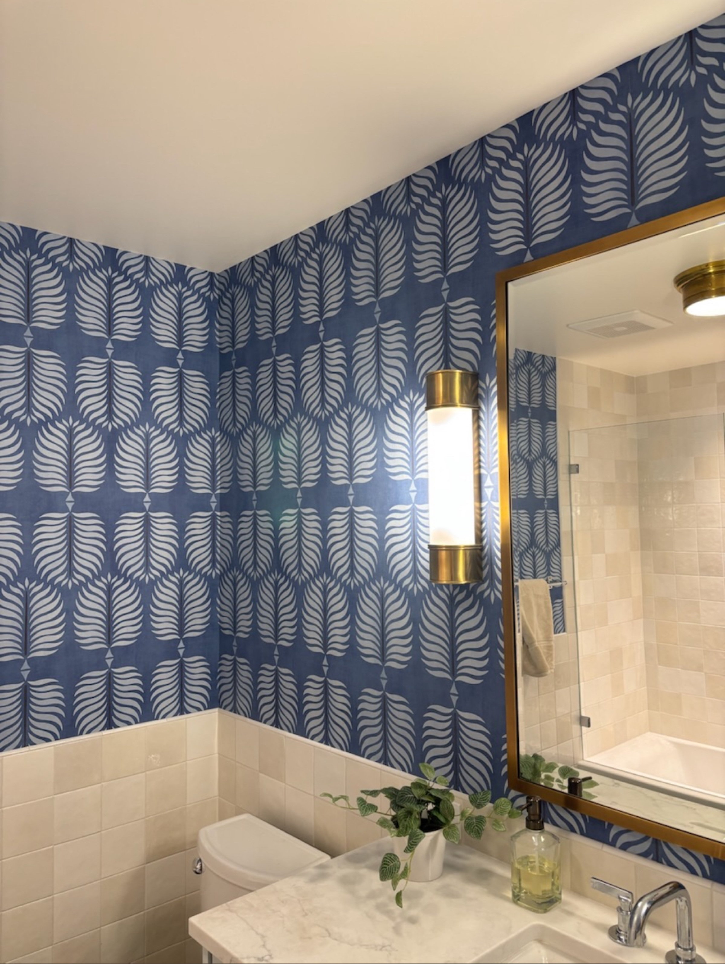 Blue patterned wallpaper installation in a finished bathroom