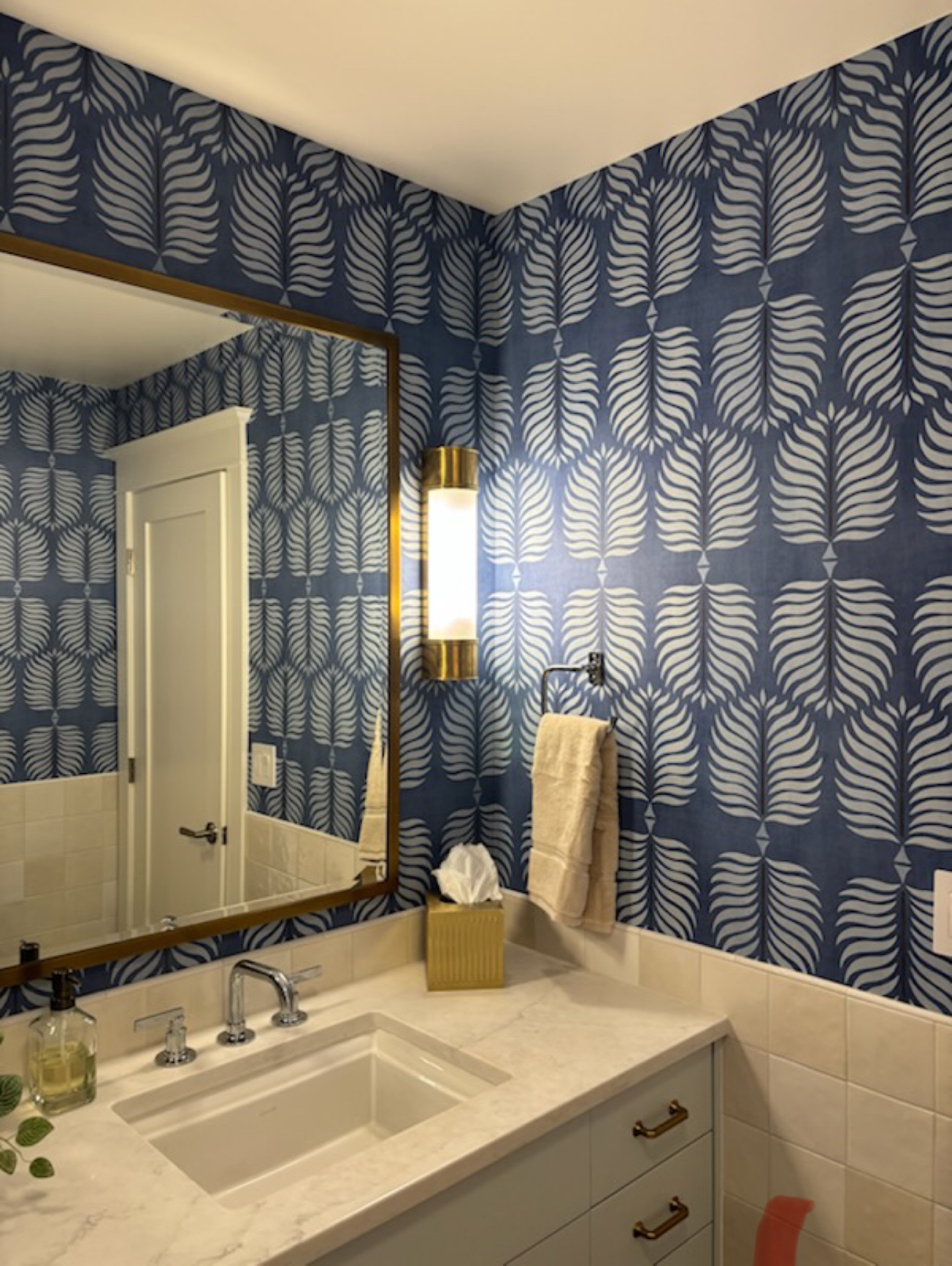 Blue patterned wallpaper installation around a bathroom vanity